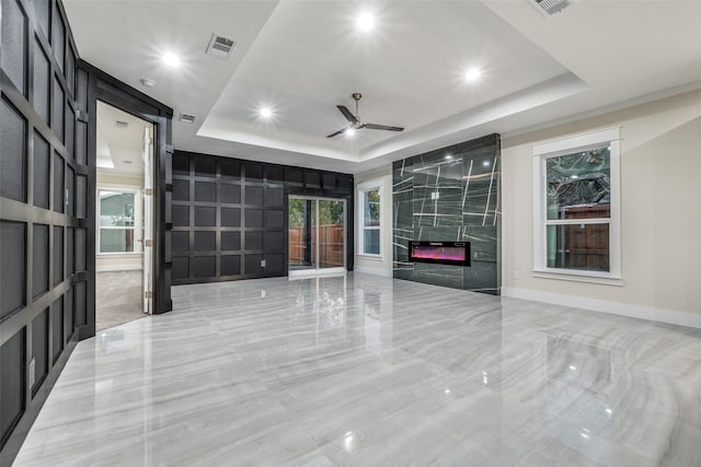 empty room featuring french doors, ceiling fan, a fireplace, and a tray ceiling