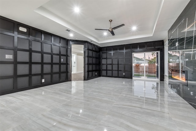 unfurnished room featuring a raised ceiling and ceiling fan