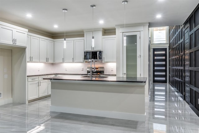 kitchen featuring hanging light fixtures, an island with sink, sink, and white cabinets