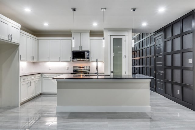 kitchen featuring sink, appliances with stainless steel finishes, white cabinetry, an island with sink, and decorative light fixtures