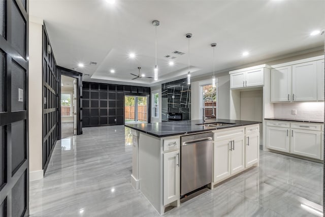 kitchen with pendant lighting, dishwasher, white cabinets, a tray ceiling, and a center island with sink