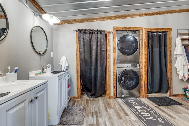 laundry room with sink, light hardwood / wood-style flooring, and stacked washer / dryer