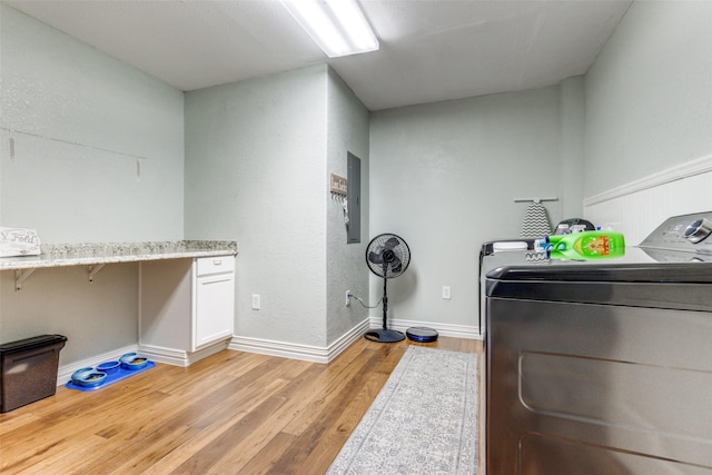 clothes washing area with washing machine and dryer and light wood-type flooring