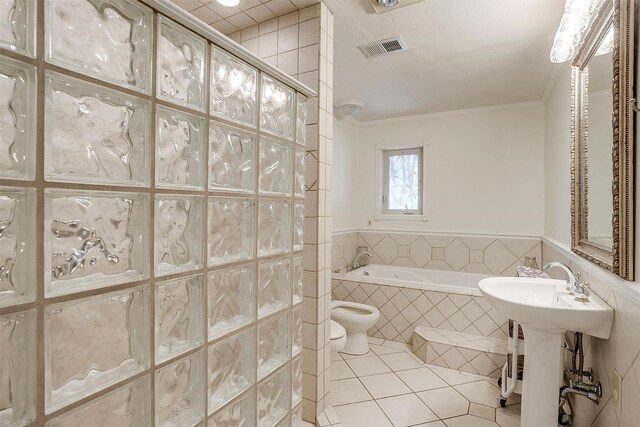 bathroom with a tile shower, tile patterned flooring, visible vents, crown molding, and a garden tub