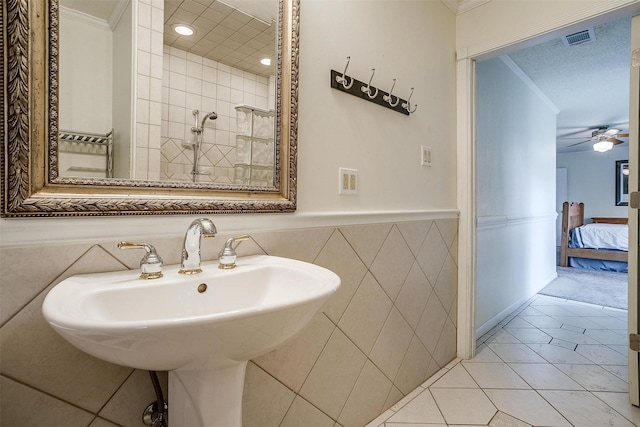 ensuite bathroom with a ceiling fan, crown molding, a sink, tile patterned flooring, and visible vents