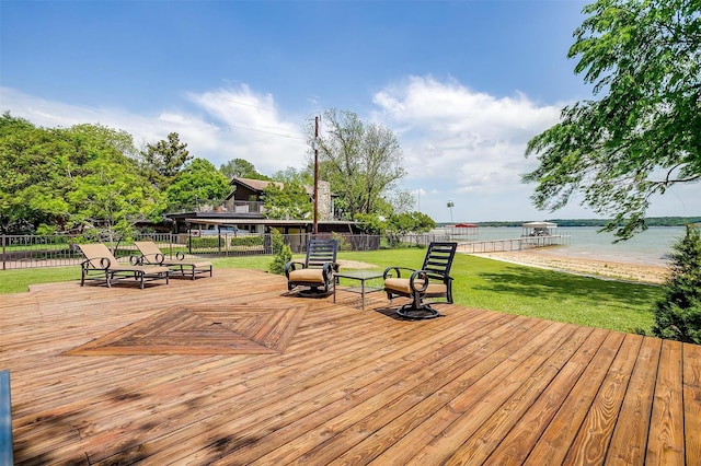 wooden terrace with fence, a lawn, and a water view