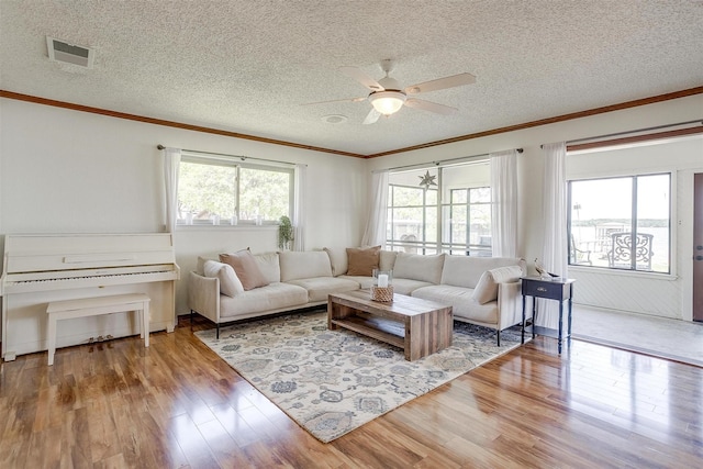 living area with ceiling fan, ornamental molding, wood finished floors, and visible vents