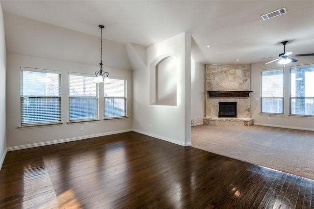 unfurnished living room with ceiling fan with notable chandelier, a fireplace, and dark hardwood / wood-style floors