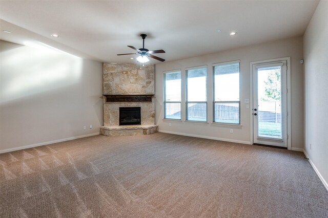 unfurnished living room with ceiling fan, light colored carpet, a stone fireplace, and sink