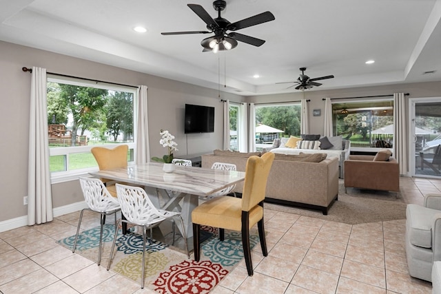 dining space featuring light tile patterned flooring and a tray ceiling