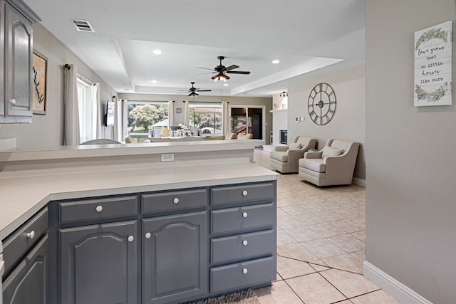 kitchen with light tile patterned flooring, a tray ceiling, and gray cabinetry