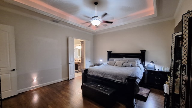 bedroom featuring ceiling fan, connected bathroom, a tray ceiling, ornamental molding, and dark hardwood / wood-style flooring