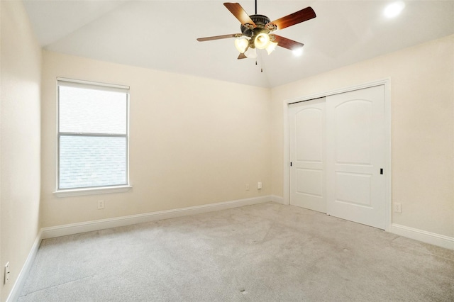 unfurnished bedroom featuring vaulted ceiling, light colored carpet, ceiling fan, and a closet