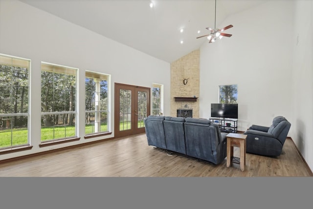 living room featuring a stone fireplace, wood-type flooring, high vaulted ceiling, and french doors