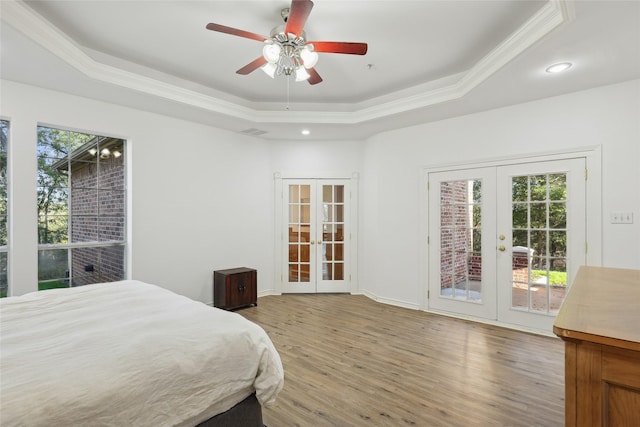 bedroom with french doors, access to outside, ornamental molding, a tray ceiling, and hardwood / wood-style flooring