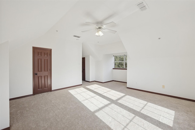 empty room featuring vaulted ceiling, light carpet, and ceiling fan