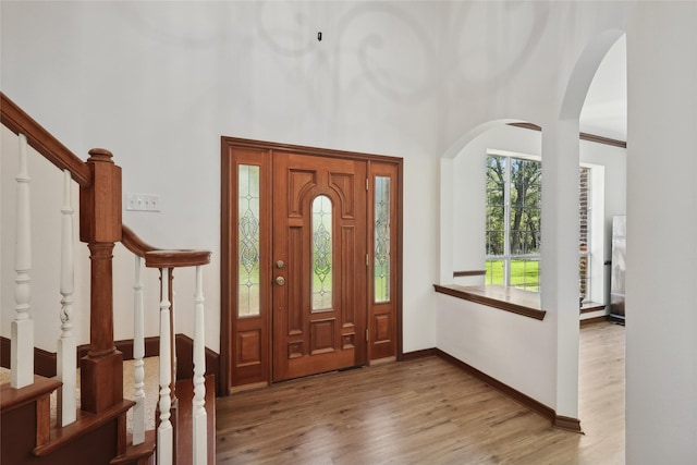 entryway featuring a towering ceiling and light wood-type flooring