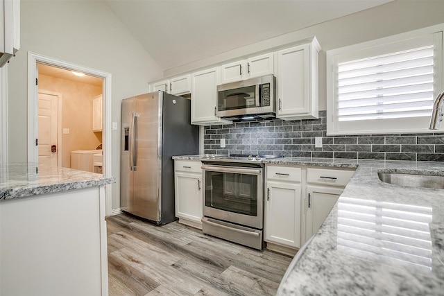 kitchen featuring white cabinetry, washing machine and clothes dryer, stainless steel appliances, and decorative backsplash