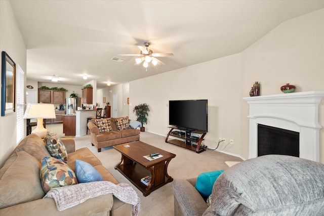 carpeted living room with ceiling fan and vaulted ceiling