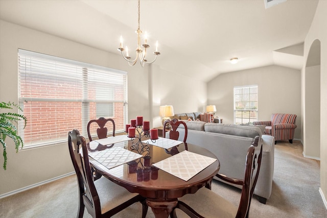 carpeted dining space with a notable chandelier and vaulted ceiling