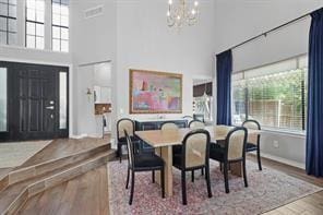 dining room with an inviting chandelier, hardwood / wood-style floors, and a high ceiling