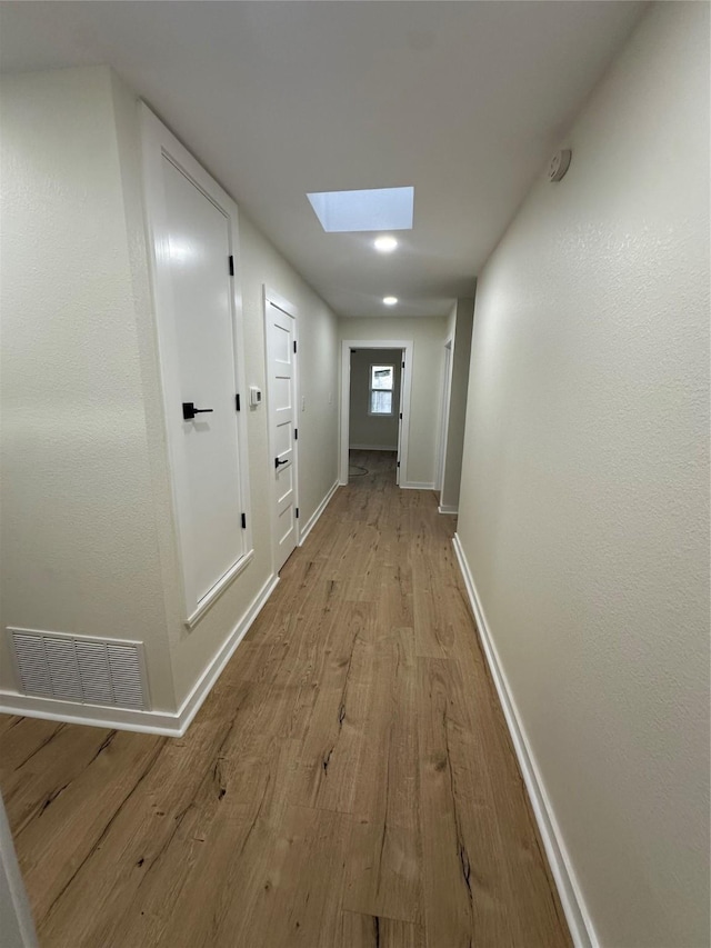 corridor featuring a skylight and light hardwood / wood-style floors