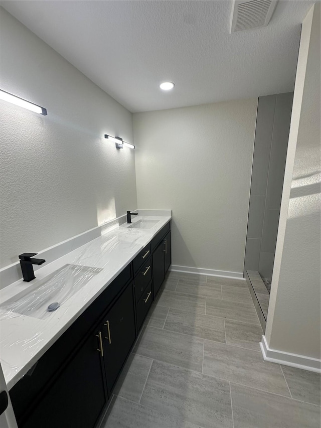 bathroom with vanity, a shower, and a textured ceiling