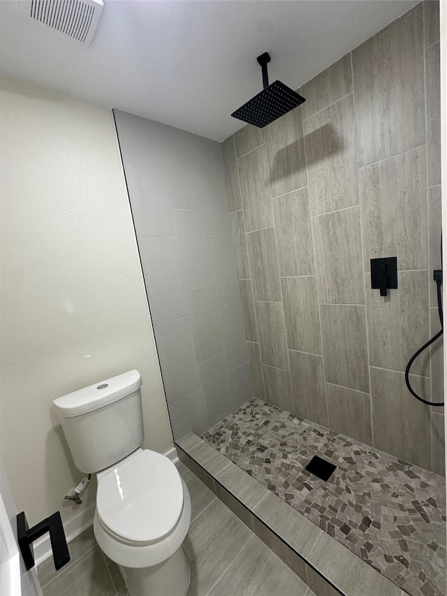 bathroom with a tile shower and toilet