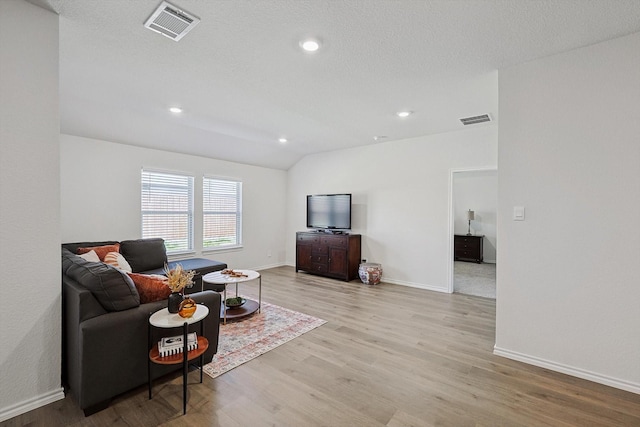 living room with lofted ceiling, a textured ceiling, and light hardwood / wood-style floors