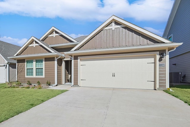 view of front of property featuring a garage, cooling unit, and a front yard