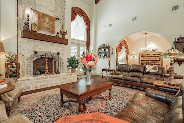 living room with a towering ceiling, a fireplace, and a notable chandelier