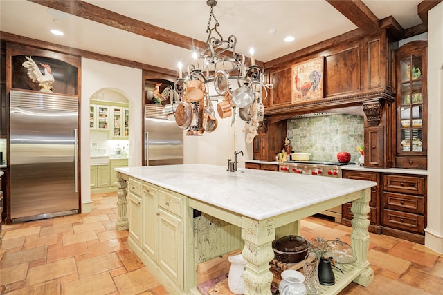 kitchen featuring tasteful backsplash, hanging light fixtures, high end appliances, a center island, and beam ceiling