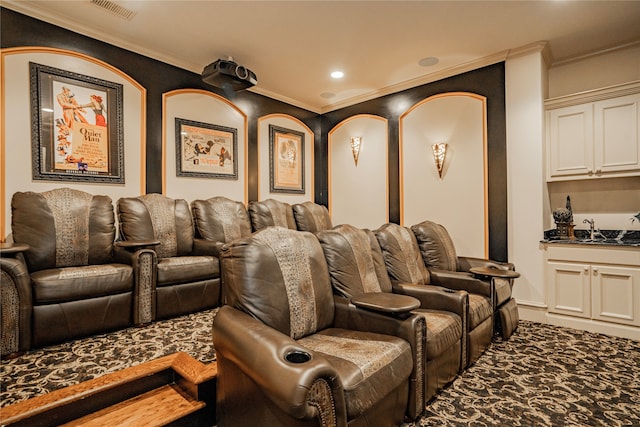 cinema room featuring sink, crown molding, and carpet flooring