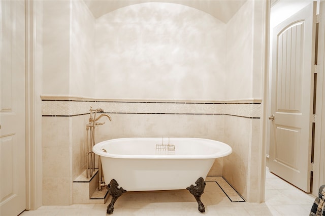 bathroom featuring tile patterned floors, tile walls, and a washtub