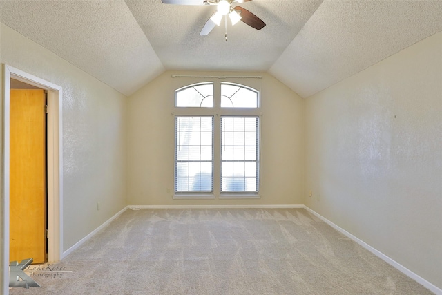 carpeted empty room featuring ceiling fan, lofted ceiling, and a textured ceiling