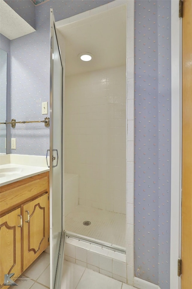 bathroom featuring vanity, tile patterned flooring, and a tile shower