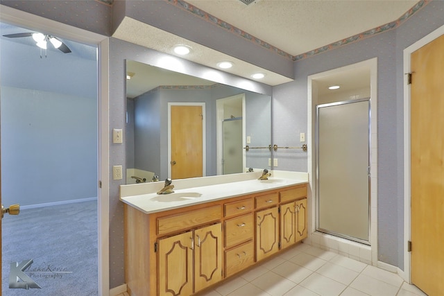 bathroom featuring ceiling fan, vanity, a shower with shower door, and tile patterned flooring