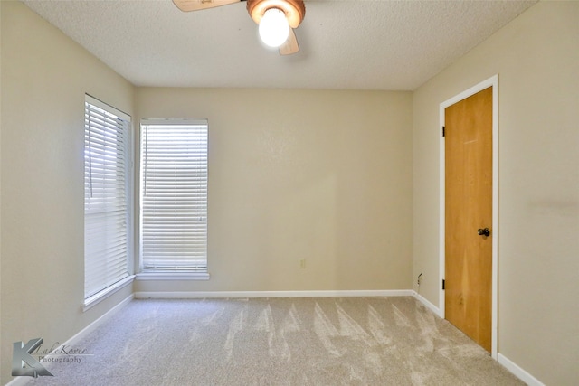 carpeted empty room with ceiling fan and a textured ceiling