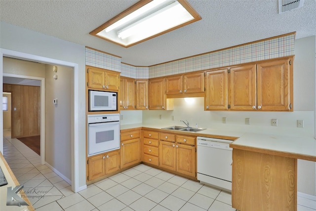 kitchen featuring light tile patterned flooring, sink, white appliances, kitchen peninsula, and a textured ceiling