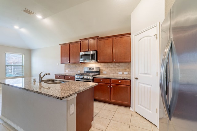 kitchen featuring lofted ceiling, sink, stainless steel appliances, light stone counters, and a center island with sink