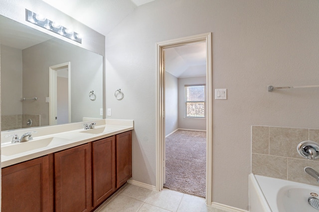 bathroom with tile patterned flooring, vanity, a tub, and vaulted ceiling