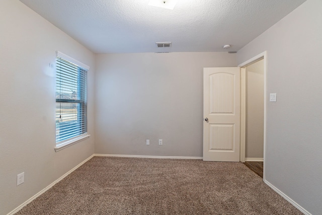 carpeted spare room with a textured ceiling