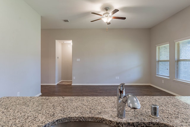 kitchen featuring dark wood-type flooring, ceiling fan, light stone countertops, and sink