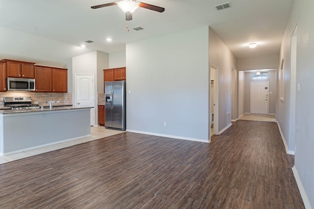 kitchen featuring decorative backsplash, light hardwood / wood-style flooring, ceiling fan, and appliances with stainless steel finishes