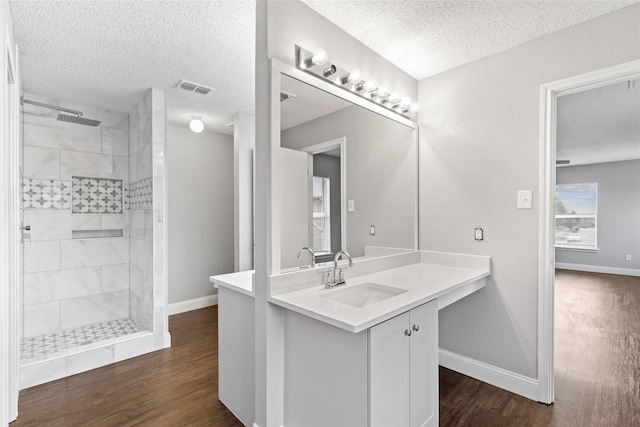 bathroom with a tile shower, vanity, hardwood / wood-style flooring, and a textured ceiling