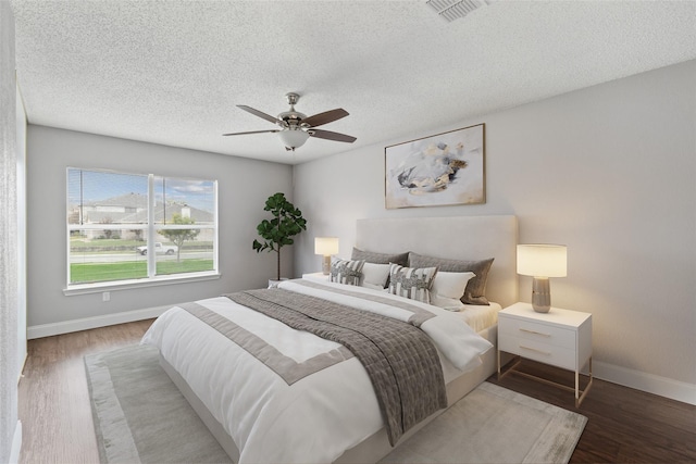 bedroom with hardwood / wood-style floors, a textured ceiling, and ceiling fan