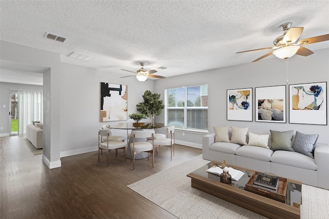 living room with ceiling fan, dark wood-type flooring, and a textured ceiling