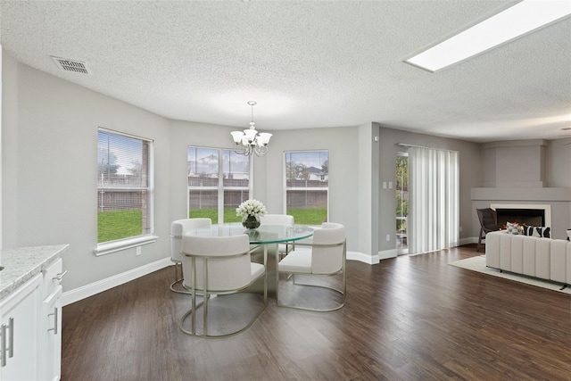 dining area with a chandelier, a textured ceiling, and dark hardwood / wood-style flooring