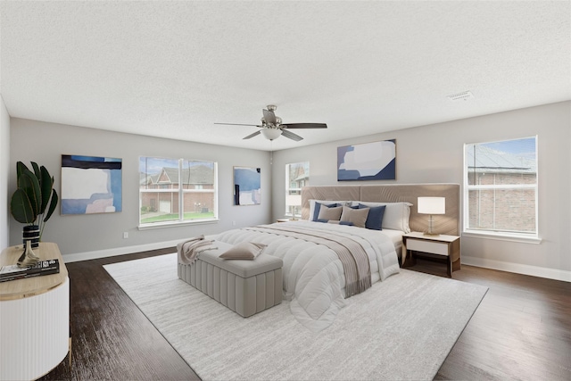 bedroom featuring multiple windows, a textured ceiling, and dark hardwood / wood-style flooring