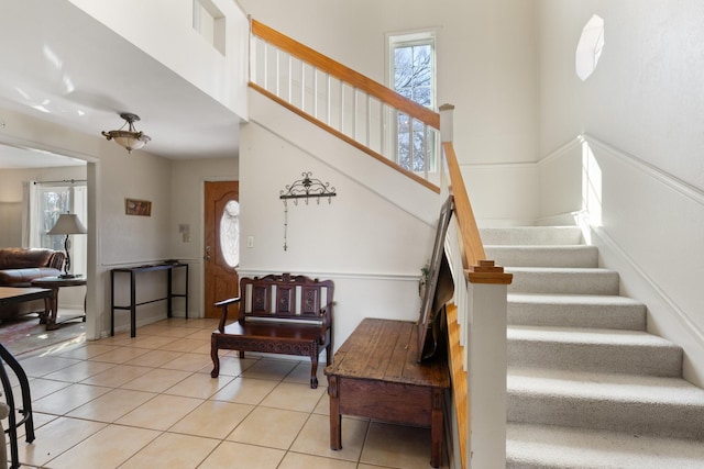 staircase featuring tile patterned flooring, a towering ceiling, and plenty of natural light